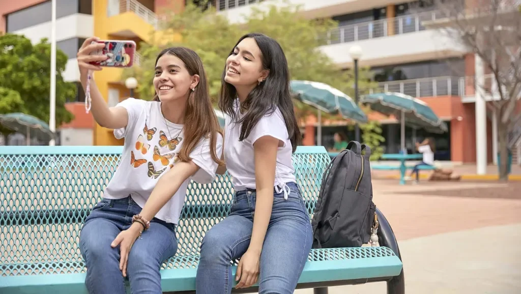 Estudiantes frente a la fachada del campus y una estatua