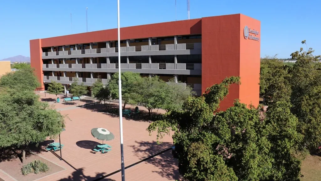 Fachada del campus con estatua y estudiantes
